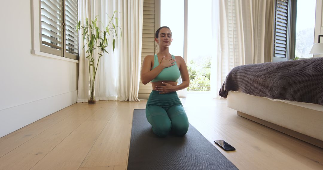 Woman practicing mindful breathing on yoga mat in bedroom