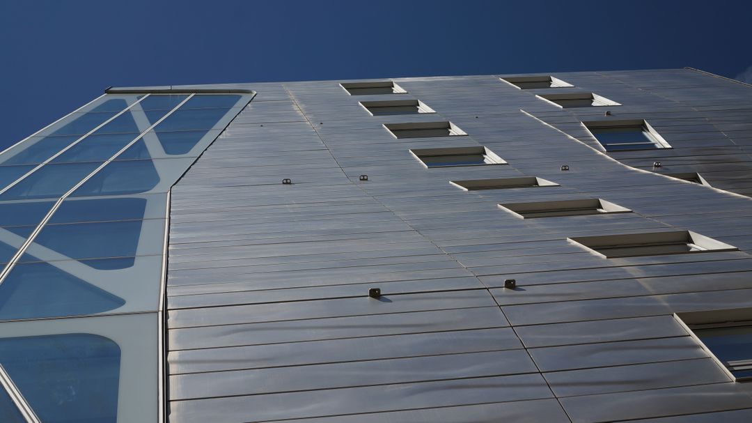 Modern building with metallic facade against clear blue sky - Free Images, Stock Photos and Pictures on Pikwizard.com