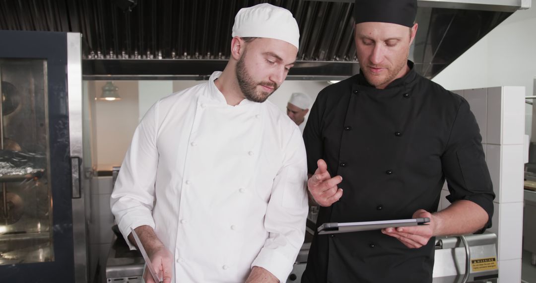 Chefs in professional kitchen discussing recipe results on tablet - Free Images, Stock Photos and Pictures on Pikwizard.com