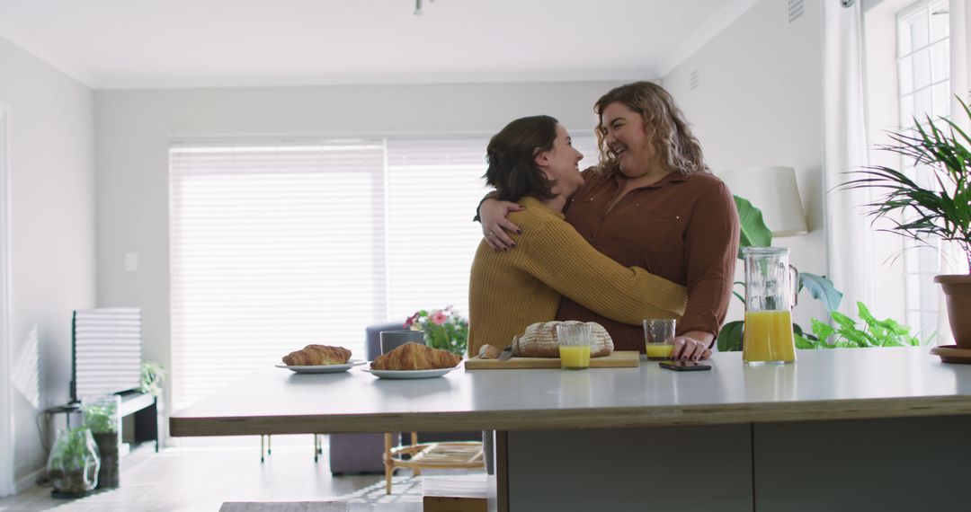 Caucasian lesbian couple embracing and smiling in kitchen - Free Images, Stock Photos and Pictures on Pikwizard.com