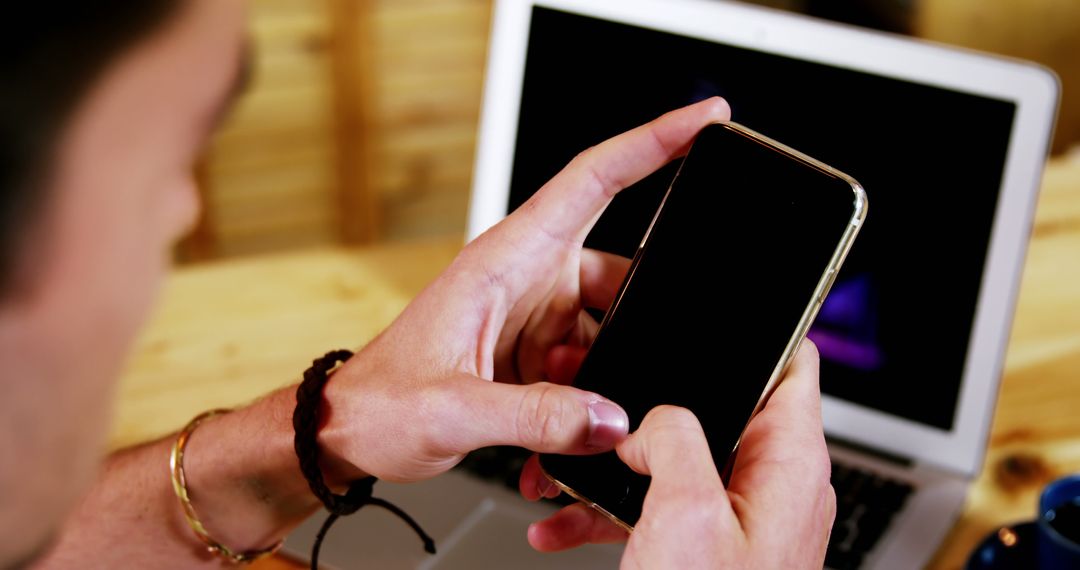 Person Holding Smartphone and Typing in Front of Laptop - Free Images, Stock Photos and Pictures on Pikwizard.com