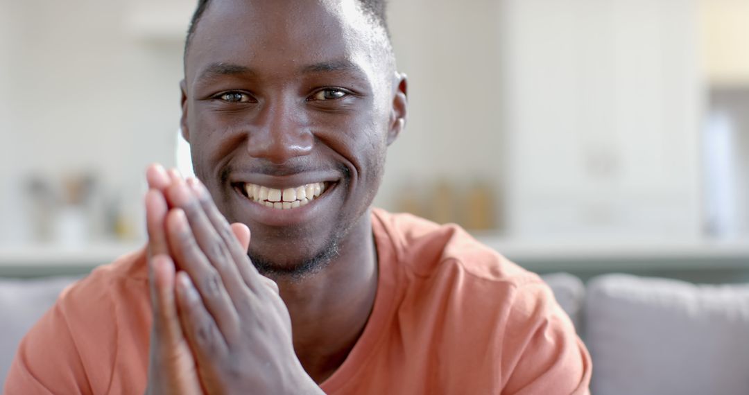 Smiling Young Man with Hands Clasped Indoors - Free Images, Stock Photos and Pictures on Pikwizard.com