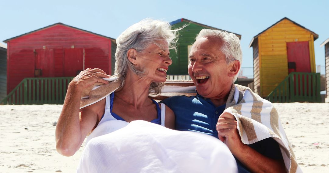 Elderly Couple Enjoying Beach Day with Colorful Beach Huts - Free Images, Stock Photos and Pictures on Pikwizard.com