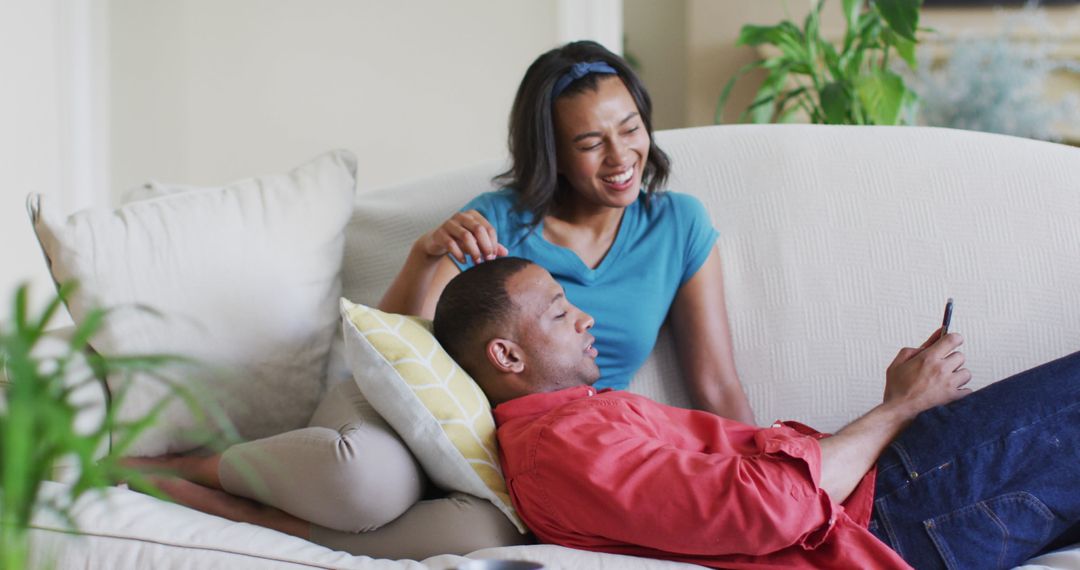Loving Couple Relaxing on Sofa Interacting with Smartphone at Home