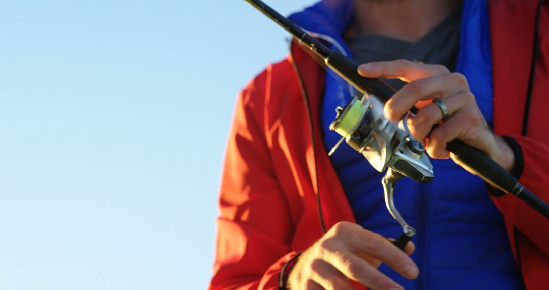 Man Preparing for Fishing with Fishing Rod in Red Jacket - Free Images, Stock Photos and Pictures on Pikwizard.com