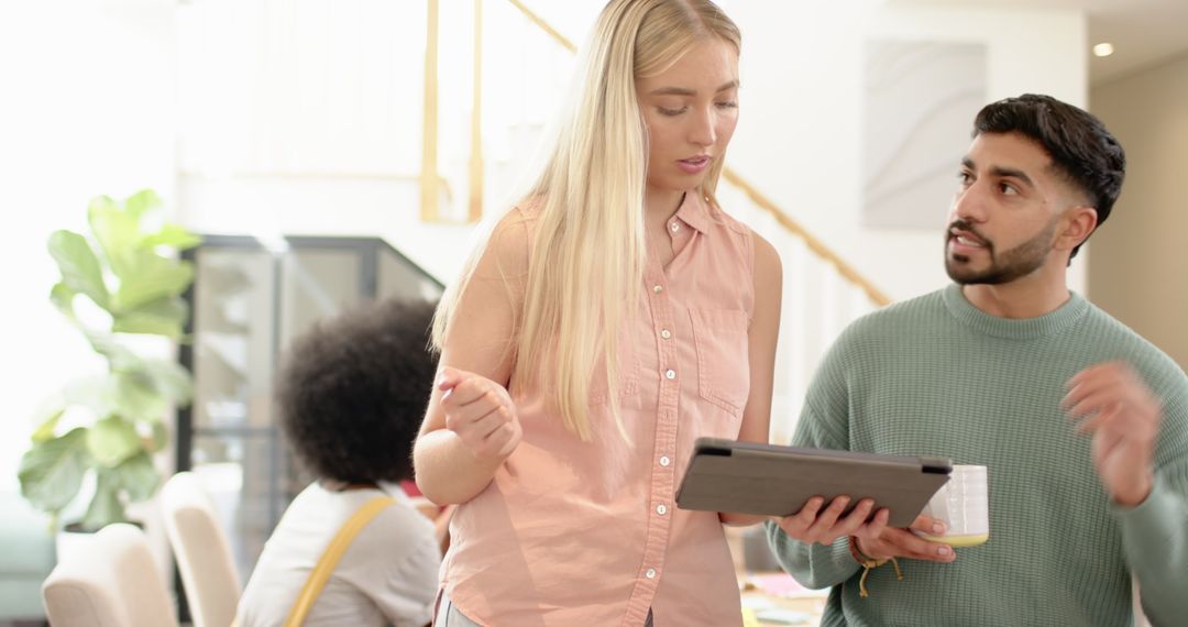 Diverse Coworkers Analyzing Data on Tablet in Modern Workspace