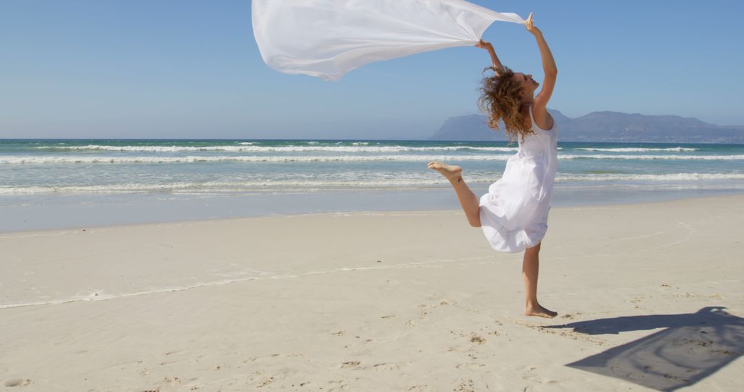 Carefree Woman Dancing with White Fabric on Sunny Beach - Free Images, Stock Photos and Pictures on Pikwizard.com