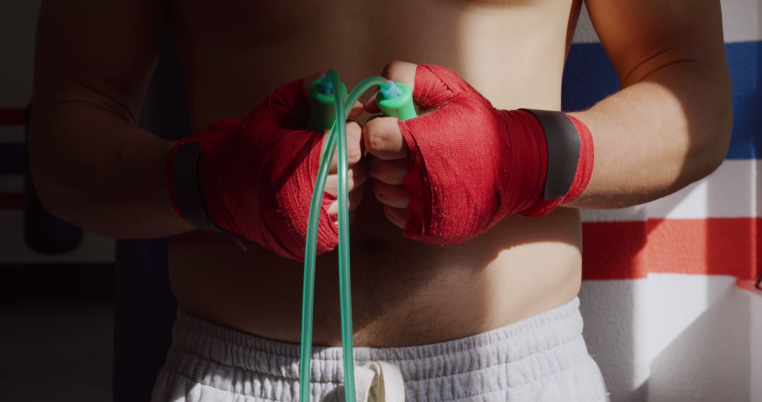 Focused Boxer with Red Hand Wraps Holding Jump Rope Before Exercise - Free Images, Stock Photos and Pictures on Pikwizard.com