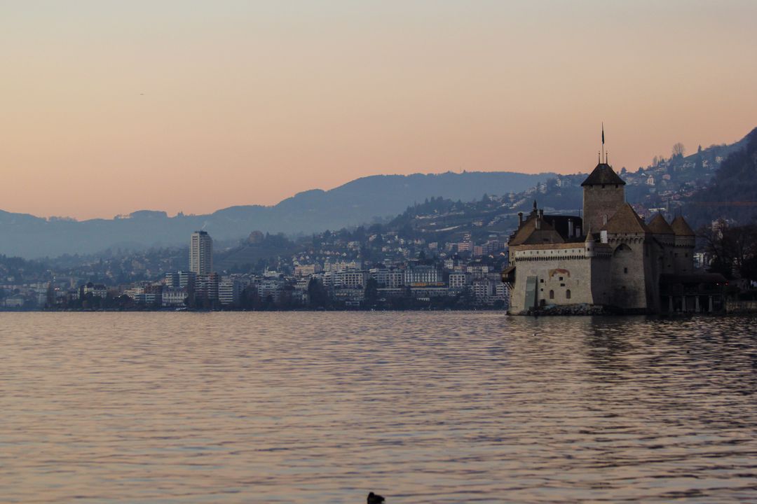 Historical Castle on Lakeshore at Sunset with Mountainous Backdrop - Free Images, Stock Photos and Pictures on Pikwizard.com