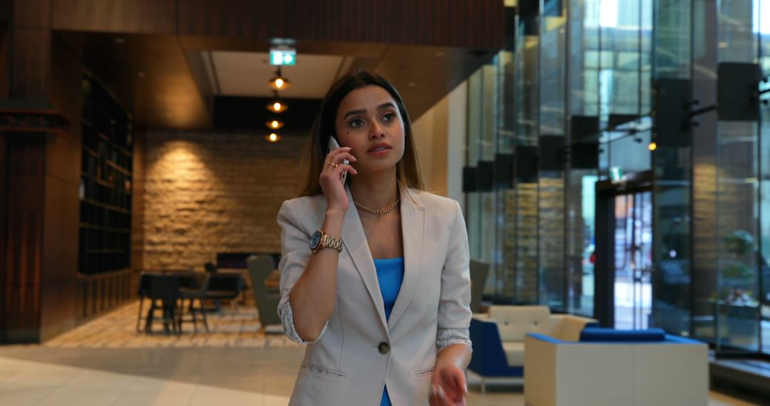 Businesswoman Talking on Mobile Phone in Modern Office Lobby - Free Images, Stock Photos and Pictures on Pikwizard.com