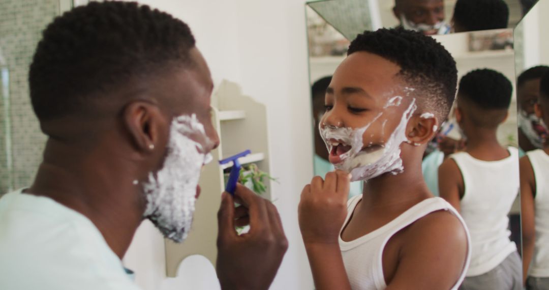 African american father and son shaving together - Free Images, Stock Photos and Pictures on Pikwizard.com
