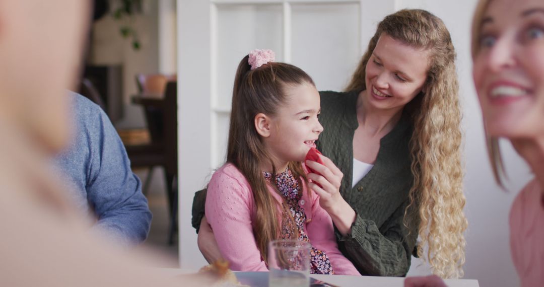 Smiling Mother Cleans Daughter's Face at Family Dinner Table