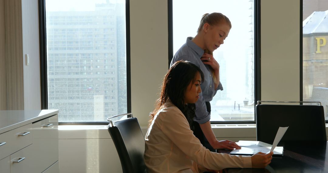 Two Businesswomen Analyzing Report in Bright Office Setting - Free Images, Stock Photos and Pictures on Pikwizard.com