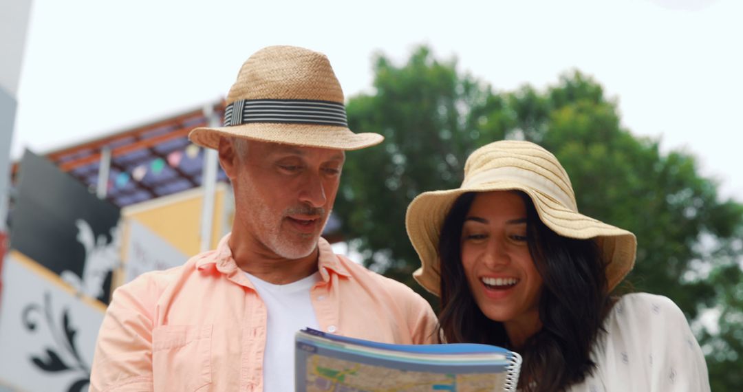 Smiling Couple Wearing Hats Reading Map, Enjoying Outdoor Adventure - Free Images, Stock Photos and Pictures on Pikwizard.com