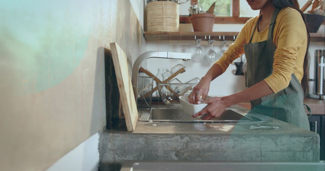 Washing dishes in rustic concrete kitchen with curved faucet and warm natural light