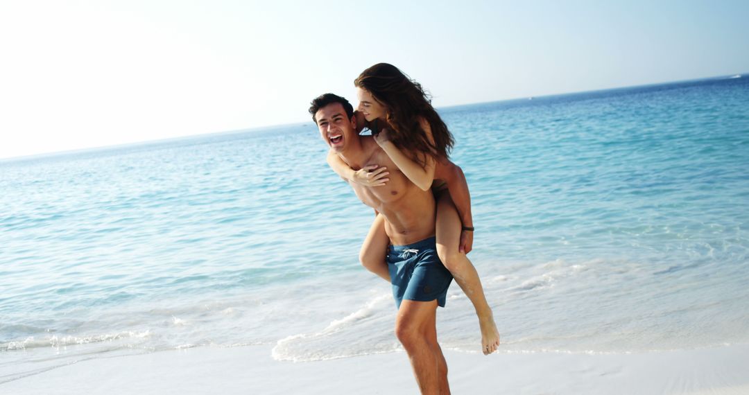 Happy couple enjoying piggyback ride on tropical beach - Free Images, Stock Photos and Pictures on Pikwizard.com