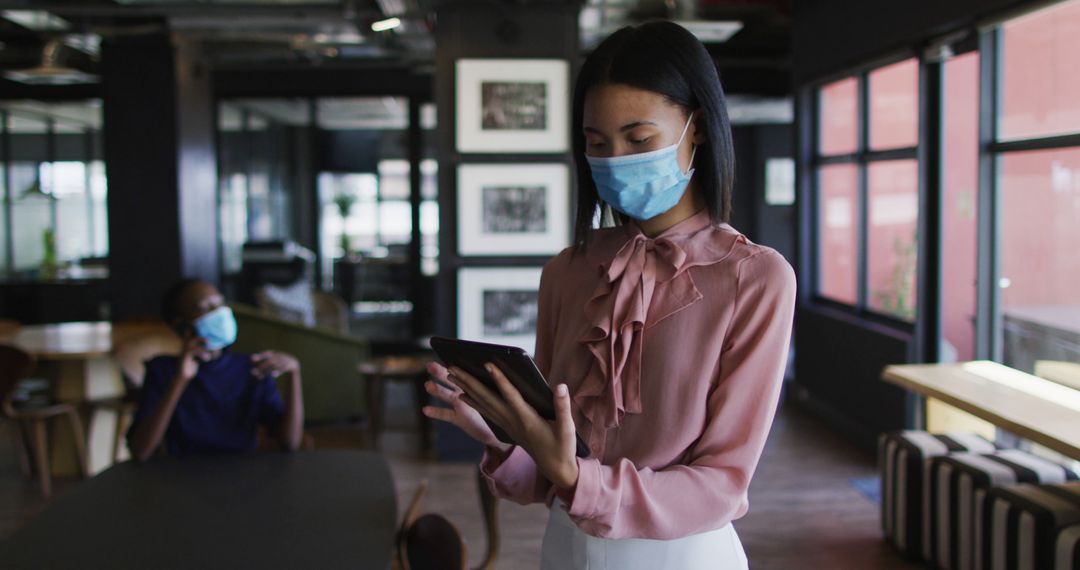 Professional Woman Using Tablet in Modern Office While Wearing Mask - Free Images, Stock Photos and Pictures on Pikwizard.com