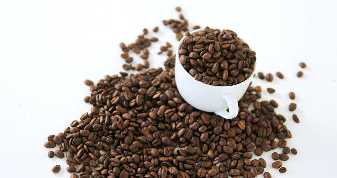 A white cup overflows with coffee beans, symbolizing the allure of raw coffee for enthusiasts. - Free Images, Stock Photos and Pictures on Pikwizard.com