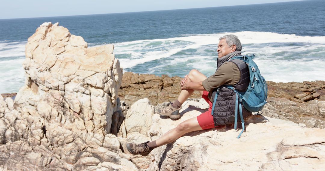 Senior Man Enjoying Coastal View Sitting on Rocks