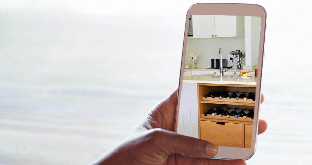 Person capturing kitchen interior on smartphone focused on wine rack - Free Images, Stock Photos and Pictures on Pikwizard.com