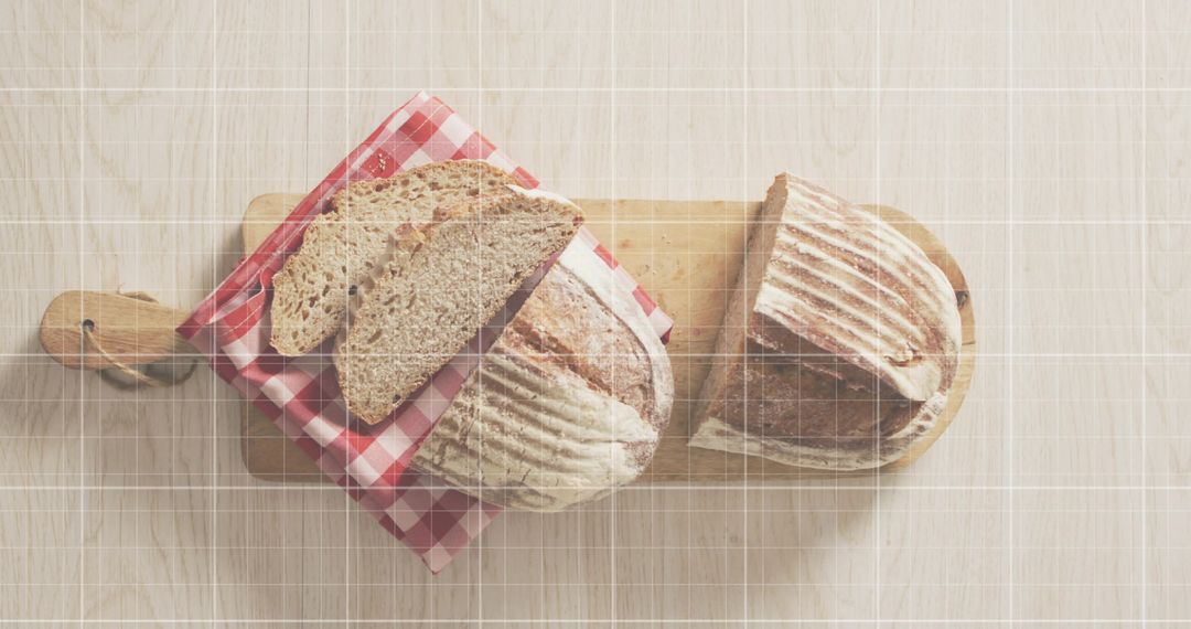 Rustic sourdough loaves on wooden cutting boards with red gingham napkin, overhead