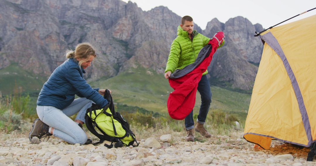 Couple Preparing Camp with Tent and Sleeping Bags in Mountainous Landscape - Free Images, Stock Photos and Pictures on Pikwizard.com