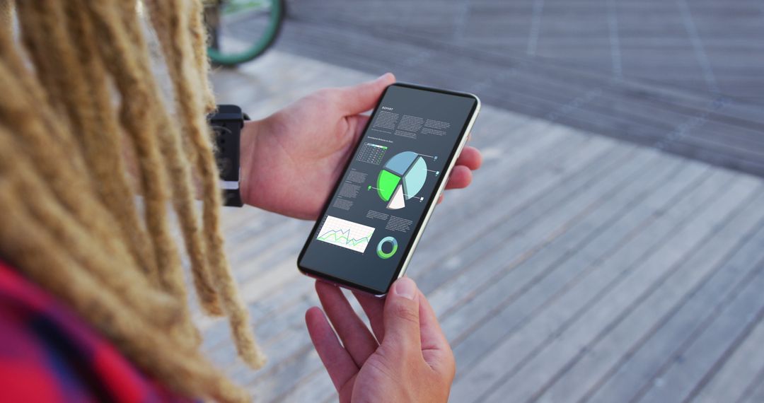 Person Analyzing Statistics on Smartphone Outdoors