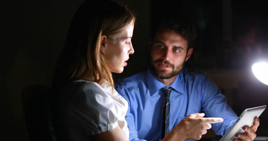 Professionals Collaborating on Tablet in Dark Office - Free Images, Stock Photos and Pictures on Pikwizard.com