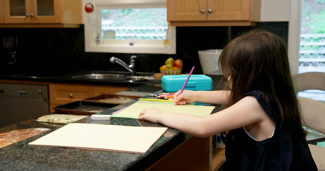 Young child drawing and coloring on kitchen countertop - Free Images, Stock Photos and Pictures on Pikwizard.com