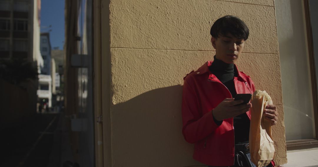 Young Man in Red Jacket Using Smartphone on Urban Street - Free Images, Stock Photos and Pictures on Pikwizard.com