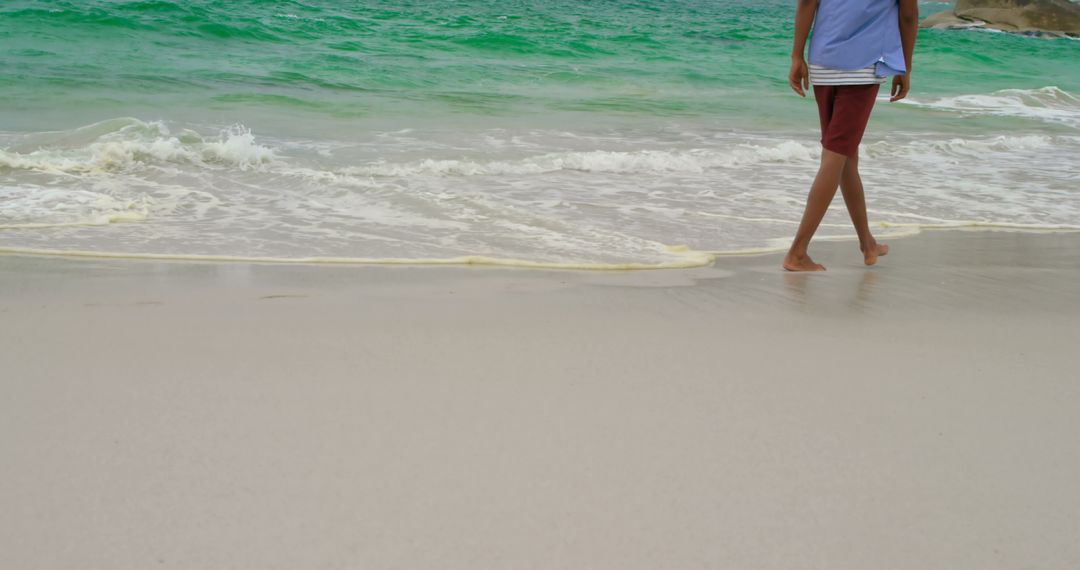 Person Walking Barefoot on Tranquil Beach Shoreline