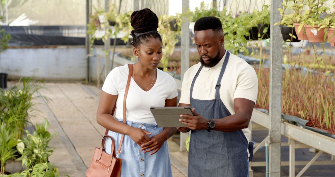 Coworkers Analyzing Plant Data on Tablet in Greenhouse