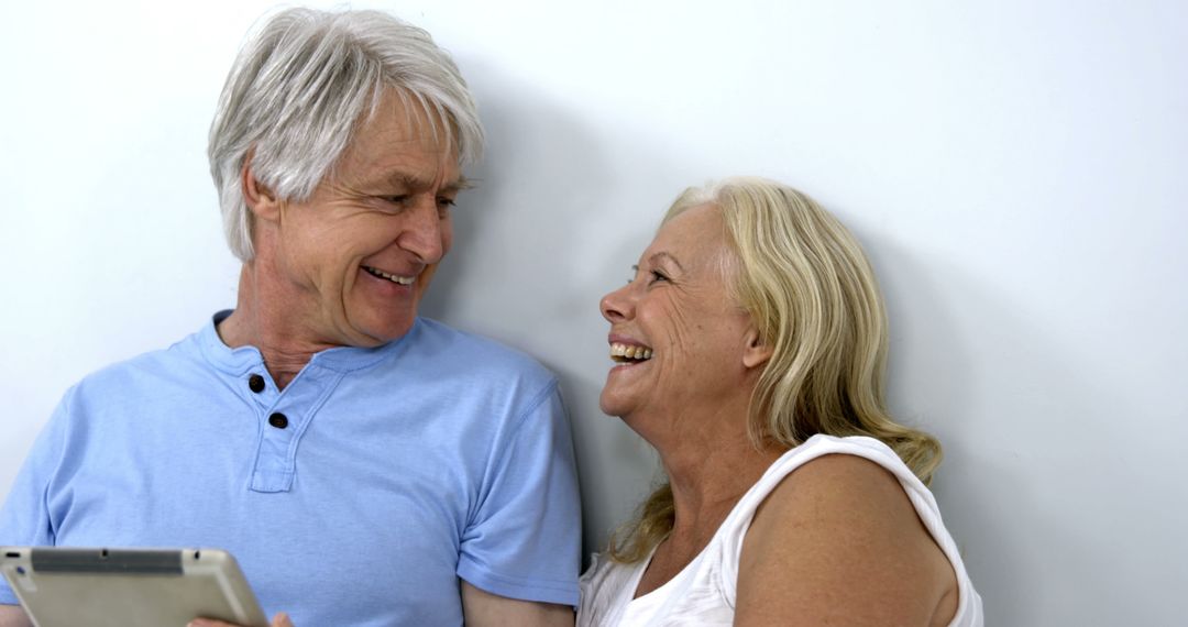 Senior Couple Laughing Together While Using Digital Tablet - Free Images, Stock Photos and Pictures on Pikwizard.com