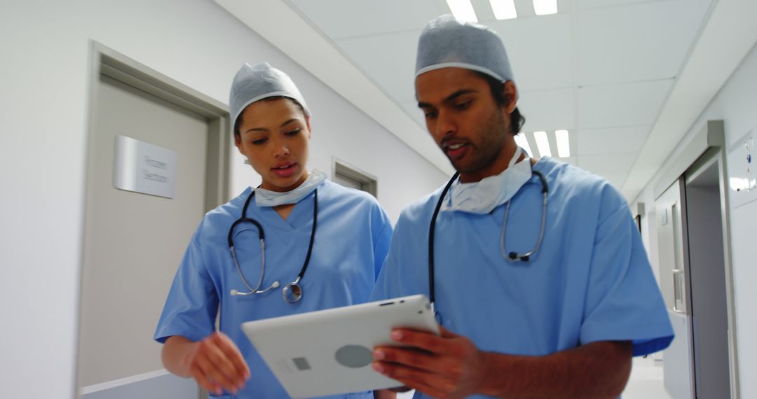 Medical Professionals Discussing Patient Data on Tablet in Hospital Corridor - Free Images, Stock Photos and Pictures on Pikwizard.com