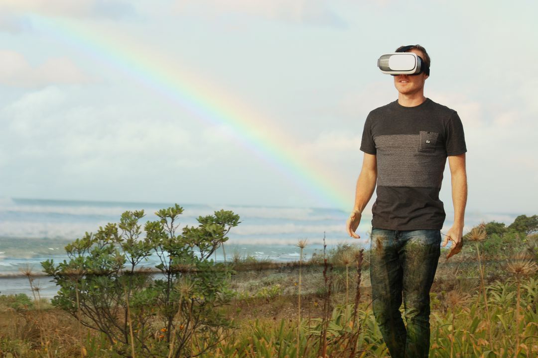 Man Using VR Headset Enjoying Virtual Outdoor Experience Near Rainbow - Free Images, Stock Photos and Pictures on Pikwizard.com