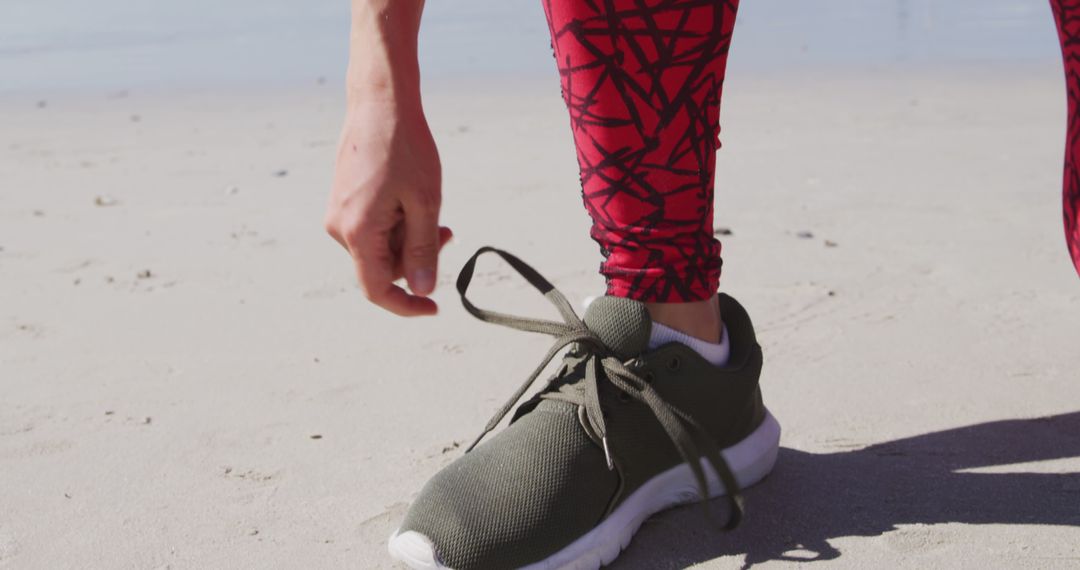 Athlete Tying Sneaker on Sandy Beach in Vibrant Leggings - Free Images, Stock Photos and Pictures on Pikwizard.com