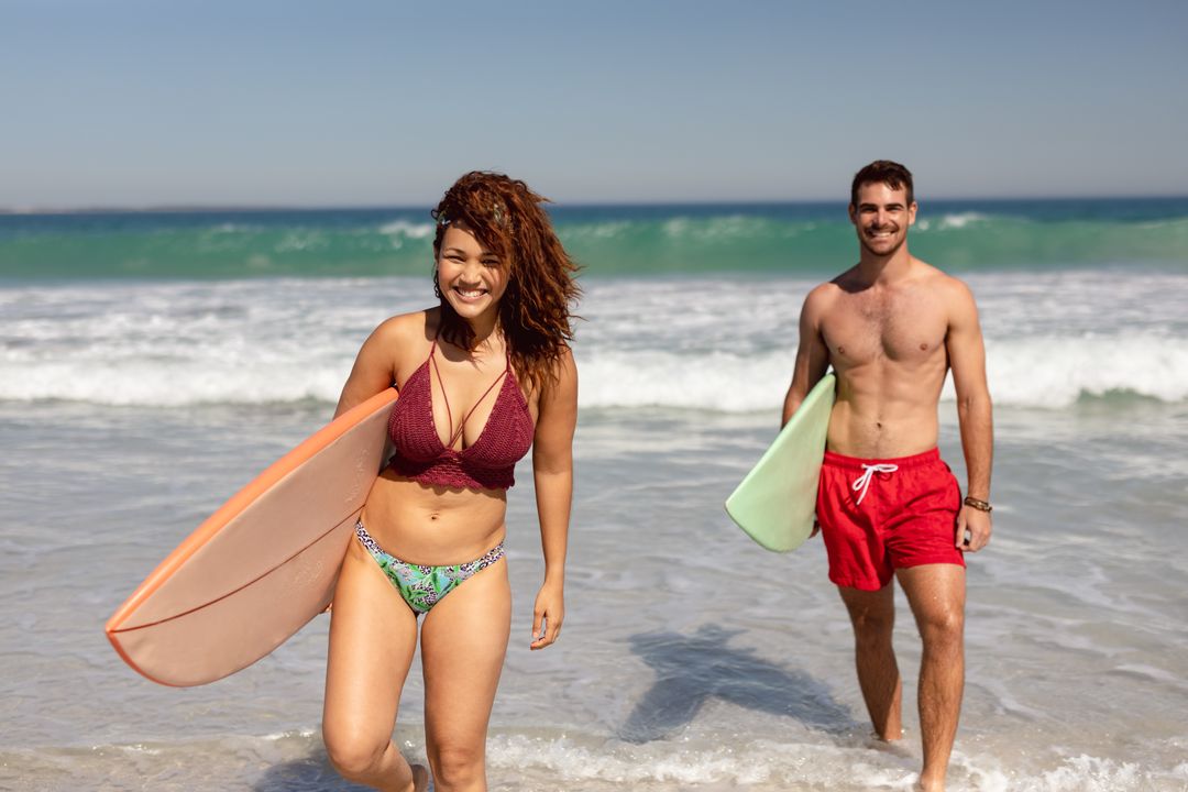 Biracial woman and Caucasian man, both colleagues, holding surfboards on beach - Free Images, Stock Photos and Pictures on Pikwizard.com