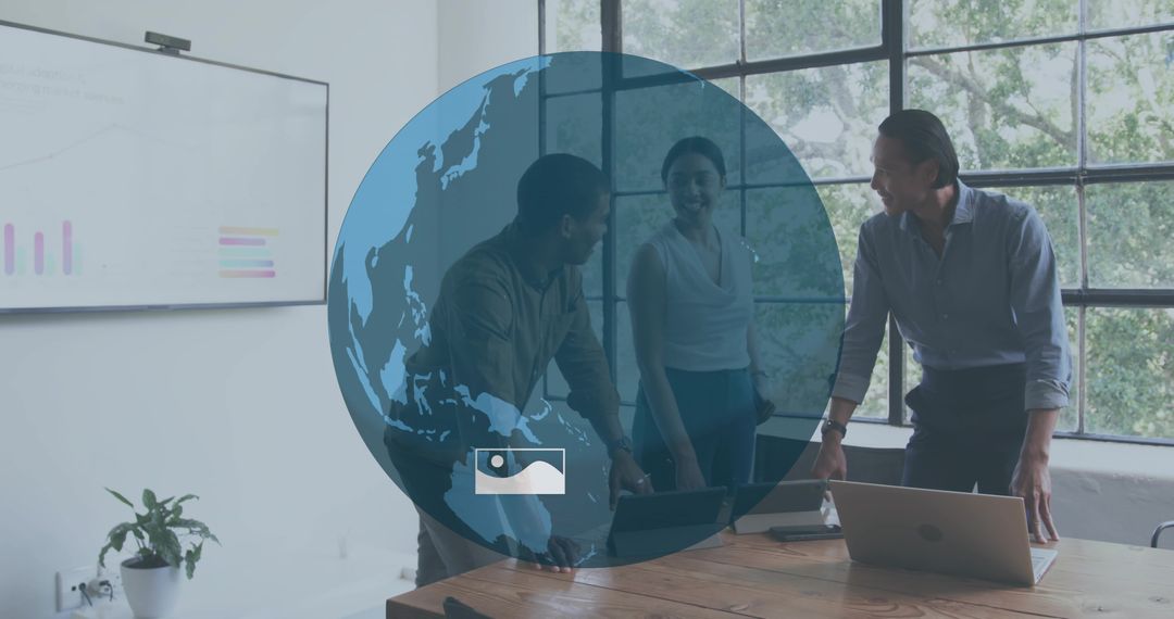 Collaborative business team leaning over laptop on wooden table with globe overlay