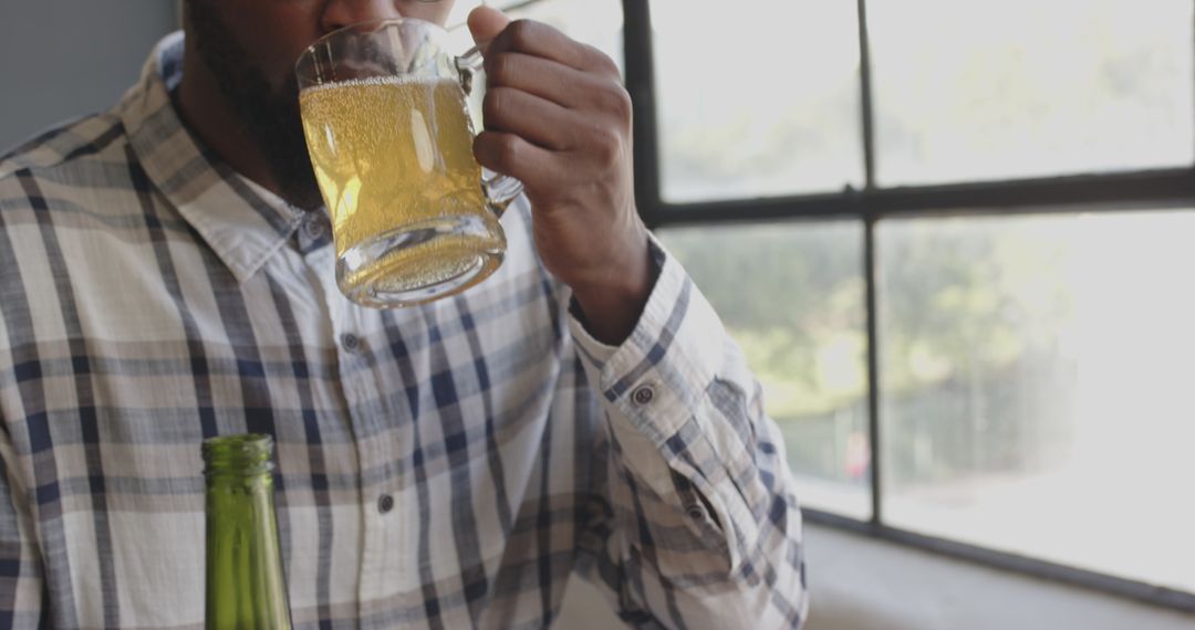 Man Enjoying Beer Mug Near Window in Casual Atmosphere