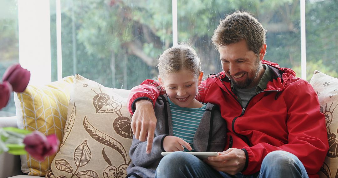 Smiling Father and Daughter Using Digital Tablet on Couch - Free Images, Stock Photos and Pictures on Pikwizard.com