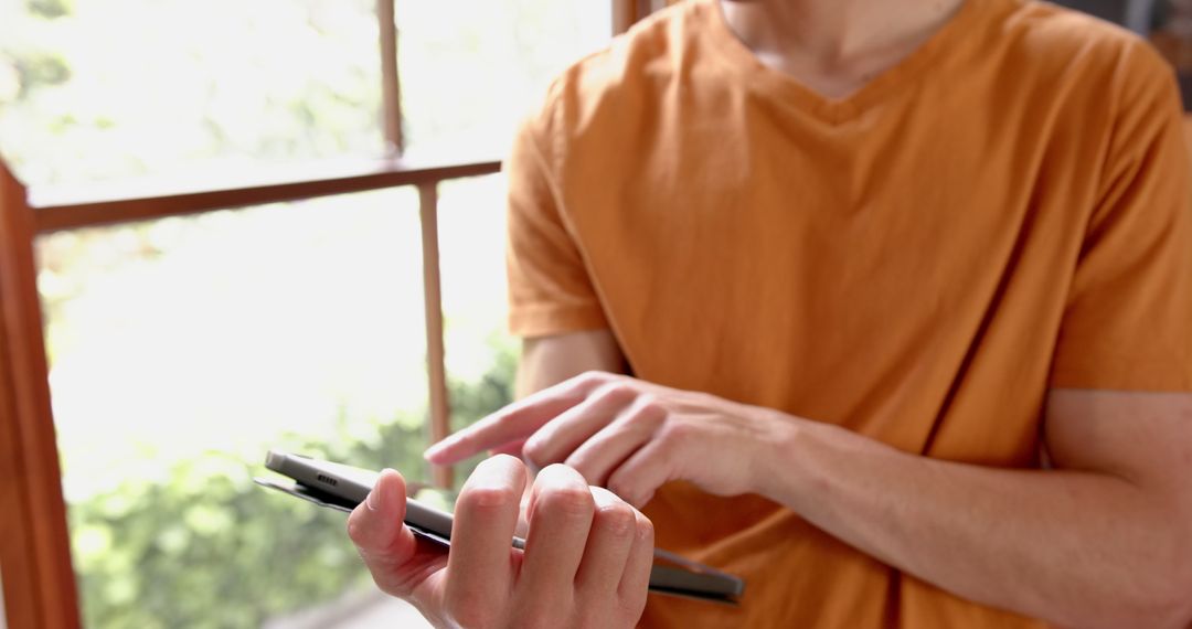 Contemplative Man Using Tablet by Sunlit Window in Relaxed Setting