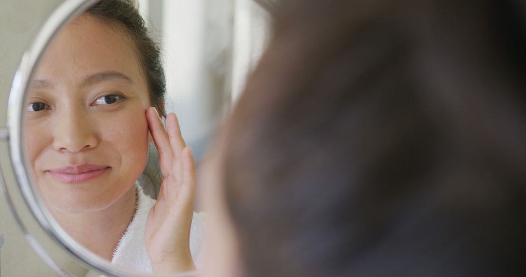 Woman Smiling and Applying Skincare Product in Front of Mirror - Free Images, Stock Photos and Pictures on Pikwizard.com