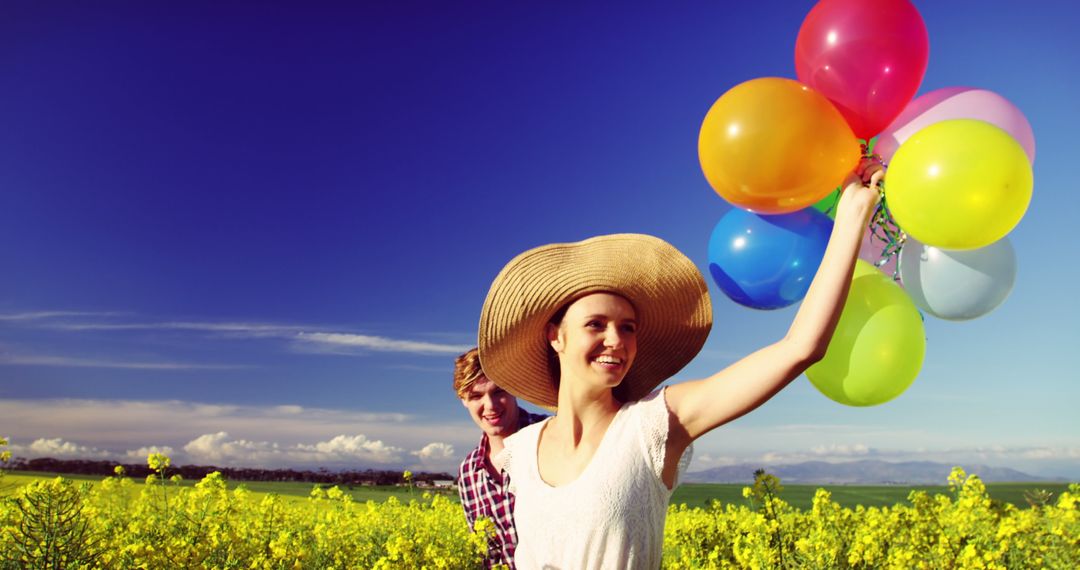 Romantic Couple Enjoying Colorful Balloons in Sunny Mustard Field Day - Free Images, Stock Photos and Pictures on Pikwizard.com