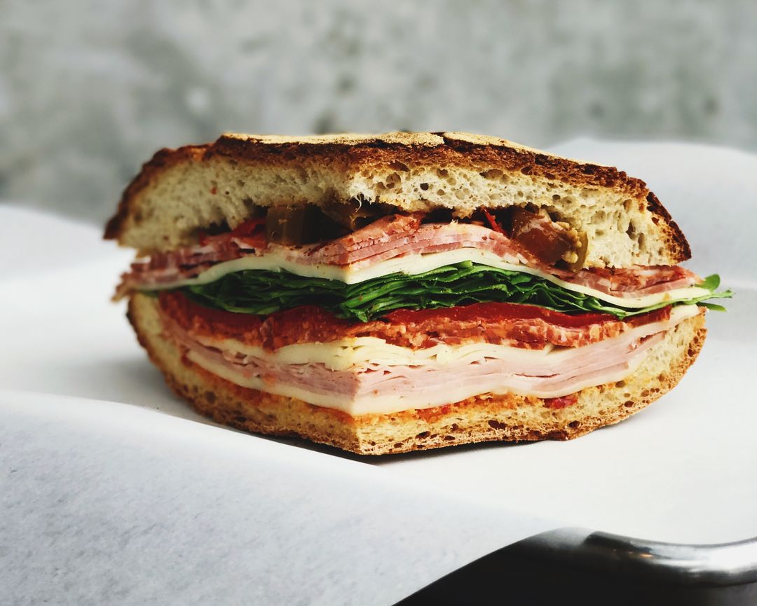 Rustic Italian Deli Sandwich with Cured Meats, Provolone and Fresh Greens on Sourdough