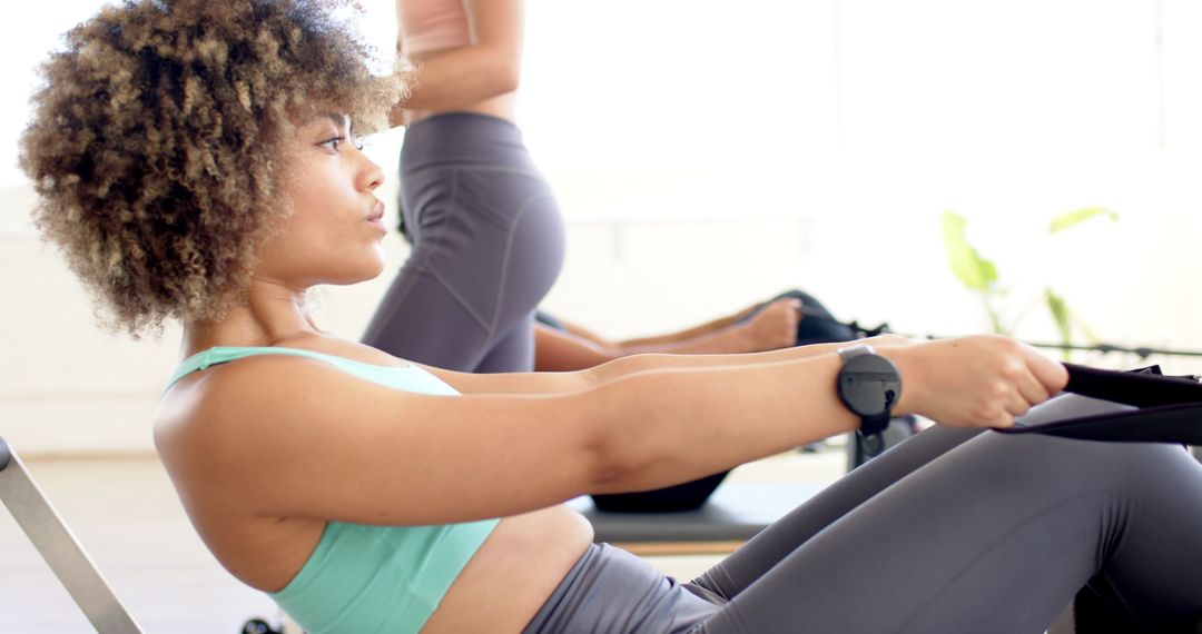 Diverse Women Exercising on Rowing Machine at Gym