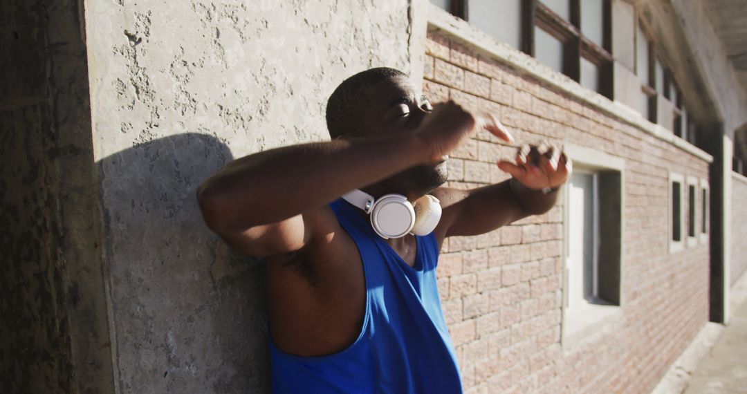 Man Relaxing Against Wall with Headphones on Neck - Free Images, Stock Photos and Pictures on Pikwizard.com