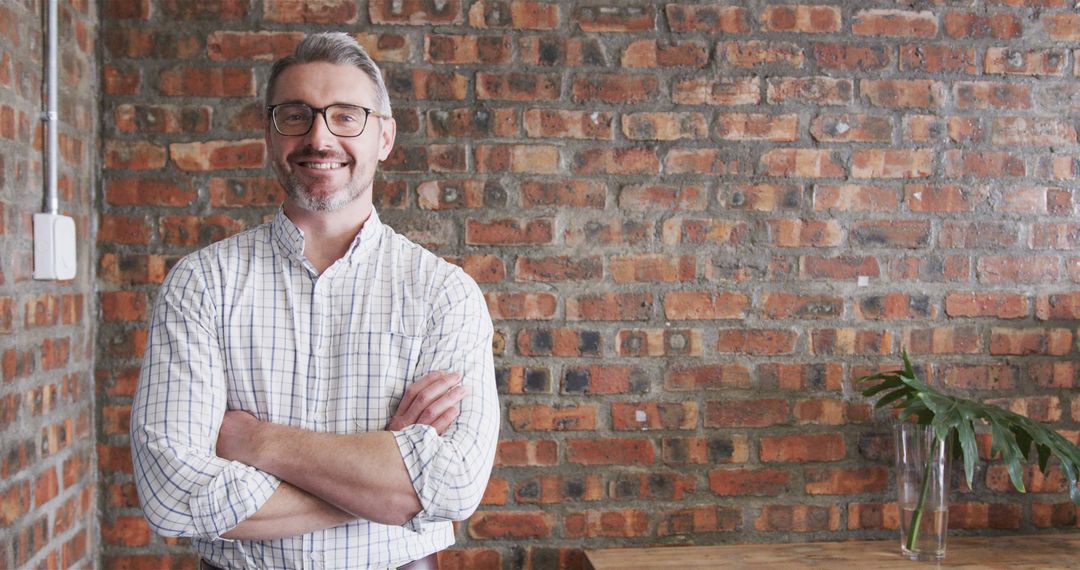 Confident Professional Man Standing Against Exposed Brick Wall - Free Images, Stock Photos and Pictures on Pikwizard.com