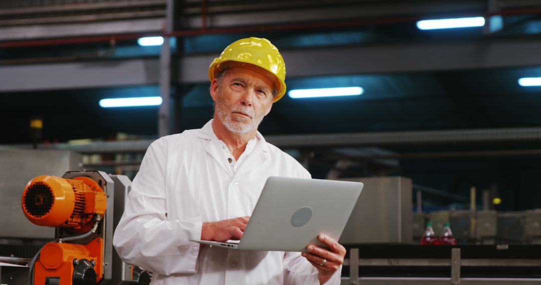 Senior Engineer Wearing Hard Hat Using Laptop in Factory - Free Images, Stock Photos and Pictures on Pikwizard.com