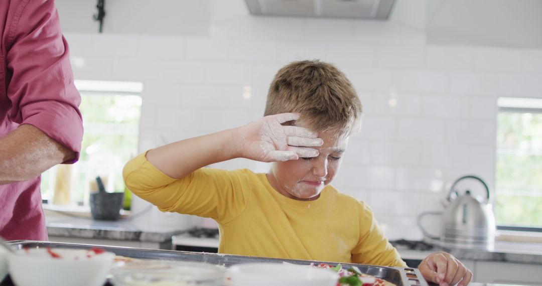 Child Wiping Flour from Face in Bright Kitchen - Free Images, Stock Photos and Pictures on Pikwizard.com