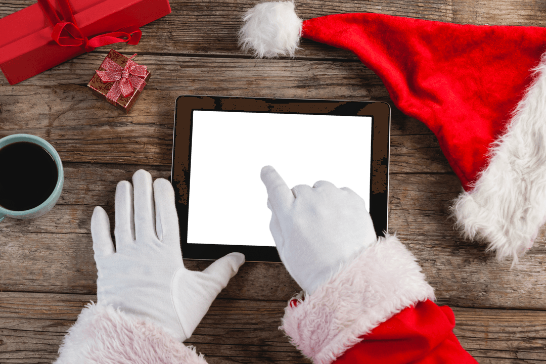 Santa's Gloved Hands Using Tablet on Rustic Wooden Table